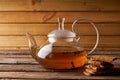 Teapot with brewed hot tea and homemade cookies on a wooden, cozy background