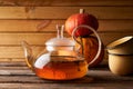 Teapot with brewed hot tea ,pumpkin fnd cookies on a wooden, cozy background