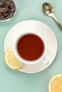 A teapot, a cup of black tea in a white ceramic mug with lemon, sugar and a spoon on a green background. Top view. Royalty Free Stock Photo