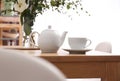 Teapot, cup and flowers on wooden dining table. Kitchen interior Royalty Free Stock Photo