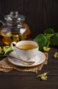 Teapot and cup with linden tea and flowers on dark wooden table Royalty Free Stock Photo