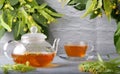 Teapot and cup with linden tea and flowers on a wooden table against a brick wall background Royalty Free Stock Photo