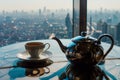 teapot and cup set on a table with a window overlooking the city