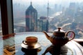teapot and cup set on a table with a window overlooking the city