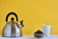 Teapot and cup on a white table with a yellow background