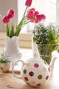 Teapot with dots and vases with beautiful spring flowers on the wooden table