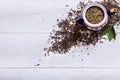 Teapot and dried tea leaves on white wooden background, green tea leaf on table, black herbal homemade hot beverage in porcelain