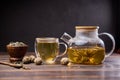 Teapot and glass cup with blooming tea flower inside on a wooden table Royalty Free Stock Photo