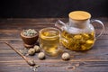 Teapot and glass cup with blooming tea flower inside on a wooden table Royalty Free Stock Photo