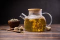 Teapot and glass cup with blooming tea flower inside on a wooden table Royalty Free Stock Photo