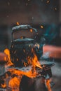 Teapot kettle on bonfire at camp site at night outdoor with flame sparks