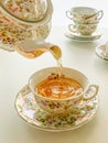 Teapot pouring tea into antique flowered cup