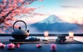 a teapot for a tea ceremony, a cup and some small zen stones lie on the mat. in the background there is a glowing cherry blossom