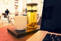 Teapot, teacup, and laptop computer on wooden desk