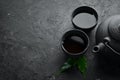 Teapot and two cups of tea on a black stone background. Royalty Free Stock Photo