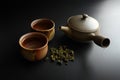 Chinese style teapot and two cups and tea leaves on the floor, with tea leaves Royalty Free Stock Photo