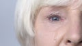 Tear flowing down cheek of sad old woman, eye discharge, lacrimation slow-mo