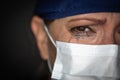 Tearful Stressed Female Doctor or Nurse Crying Wearing Medical Face Mask on Dark Background