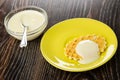 Teaspoon in bowl with condensed milk, cookie with milk in saucer on wooden table