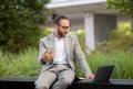 Tech-savvy young businessman working with laptop and smartphone outdoors Royalty Free Stock Photo