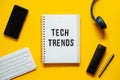 Tech trends, Top New Technology Trends. Word trends on open notepad with different gadgets and devices on yellow