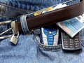 Banknotes and mobile phones on denim pants