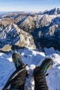 Technical mountain boots with crampons on the climber`s legs and two ice axes with a beautiful mountain landscape in the
