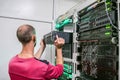 Technical Support Engineer performs the installation of a new server in a rack with computer equipment. The man is working in the