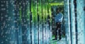 IT technician analyzing server rack in data center corridor, with tablet and floating binary code Royalty Free Stock Photo