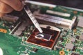 Technician applying thermal paste with syringe on the CPU processor on motherboard laptop Royalty Free Stock Photo