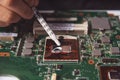 Technician applying thermal paste with syringe on the CPU processor on motherboard laptop