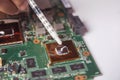 Technician applying thermal paste with syringe on the GPU processor on motherboard laptop