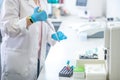 Technician in blue gloves pouring blood sample into the test tube in the laboratory