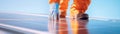 Technician in bright safety gear meticulously cleans a solar panel on a rooftop under a clear sky. Sunlight highlights Royalty Free Stock Photo