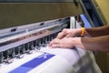 Technician catching a vinyl paper on large inkjet printer