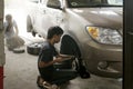 Beside of technician are changing front wheel in garage. Royalty Free Stock Photo