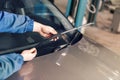 Technician is changing windscreen wipers on a car station.