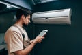 Technician checks air conditioning unit using tablet in modern indoor setting during day Royalty Free Stock Photo