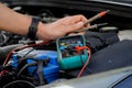 technician checks the battery using a voltmeter capacity tester,auto mechanic uses a multimeter voltmeter to check the voltage Royalty Free Stock Photo