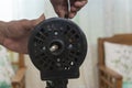 A technician checks the oscillation knob of a dismantled electric stand fan under repair or cleaning