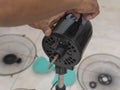 A technician checks the oscillation knob of a dismantled electric stand fan under repair or cleaning