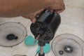 A technician checks the oscillation knob of a dismantled electric stand fan under repair or cleaning