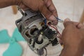 A technician checks the wiring of a defective old oscillating electric fan