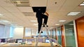 A technician climbs a ladder in a spacious office, working above the ceiling tiles. Royalty Free Stock Photo