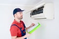 Technician with clipboard looking at air conditioner for installation quote Royalty Free Stock Photo