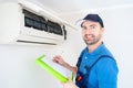 Technician with clipboard looking at air conditioner for installation quote Royalty Free Stock Photo