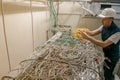 A technician connects a fiber optic internet cable in a server room. A worker in a helmet dissolves many twisted wires. A man on