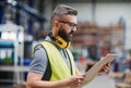 Technician or engineer with protective headphones standing in industrial factory. Royalty Free Stock Photo