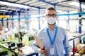 Technician or engineer with protective mask working in industrial factory, standing. Royalty Free Stock Photo