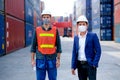 Technician or engineer workers stand in front of shipping container with one hold infrared thermometer and manager also wear face